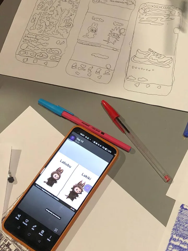 Someone is showing a meme on the phone: which one is labubu and which is lakiki? On the table, the meme has been traced on a sheet of paper.