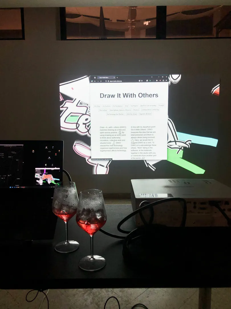 Guess what? A picture of two spritz select in front of a projection. In the projections there are some doodles and colorful drawing in the background, while a browser window is opened on the homepage of this very website.