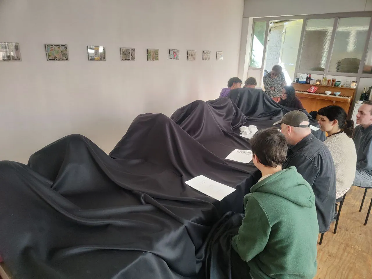 People hidden under a black cloth to trace their phone