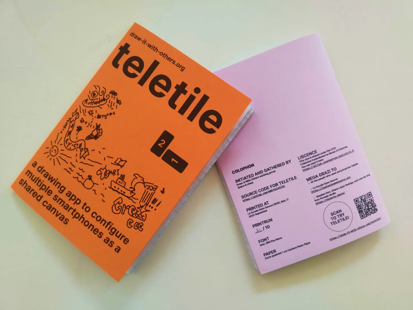 Picture of two copies of the zine. The covers are printed on paper of different colors, so each zine is different.