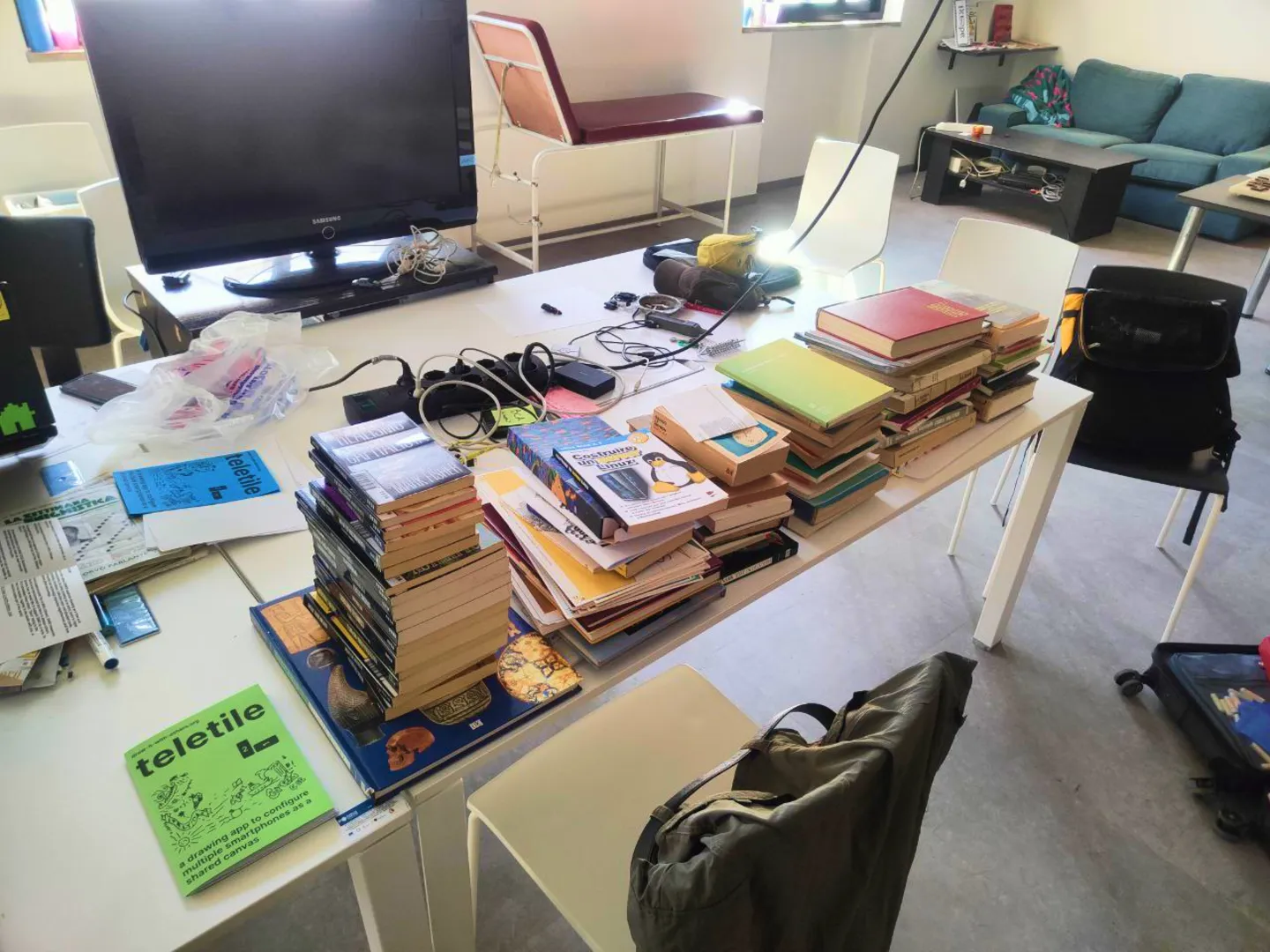 Picture of a working desk with a copy of the zine and a massive amount of books scattered around the table.