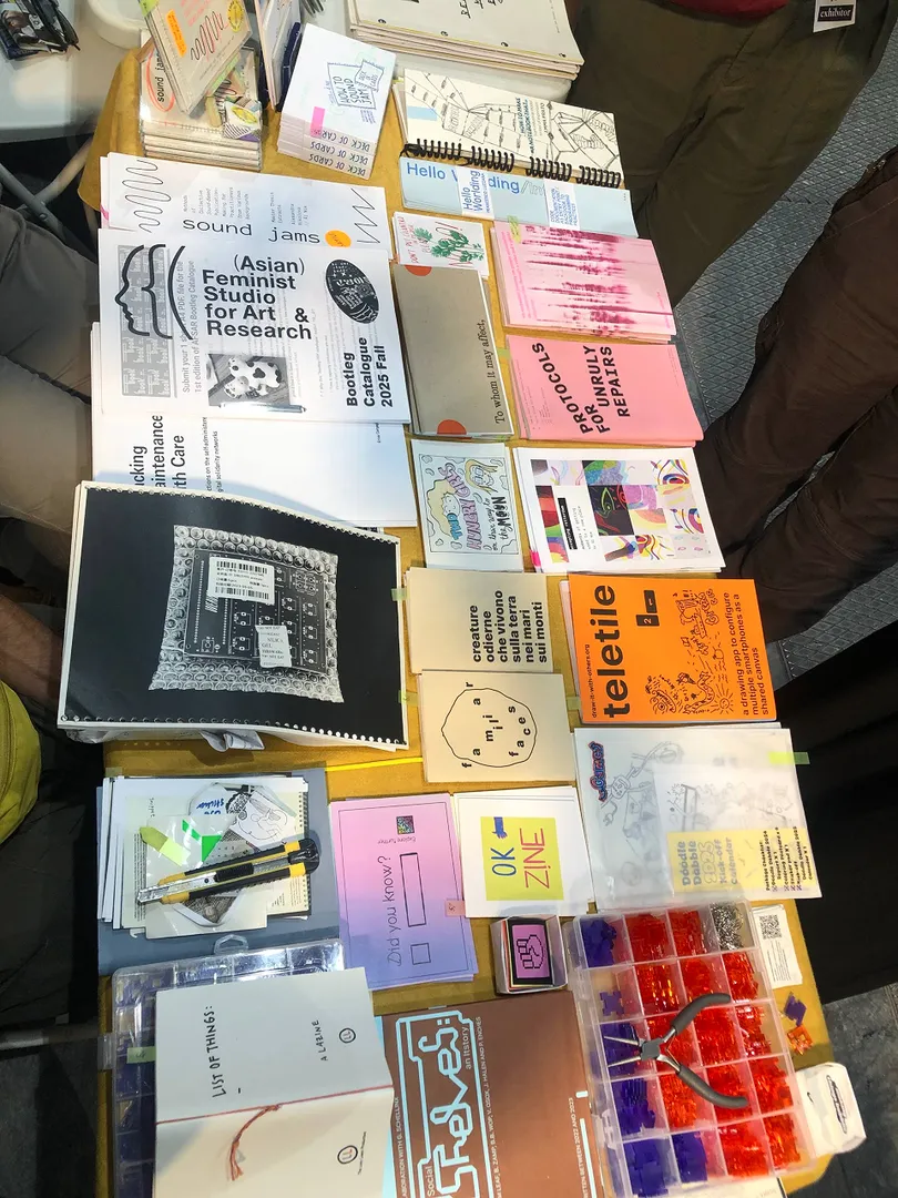 A table full of publications and zines at a book fair. Colorful collection of formats and mediums. Funny people for sure.