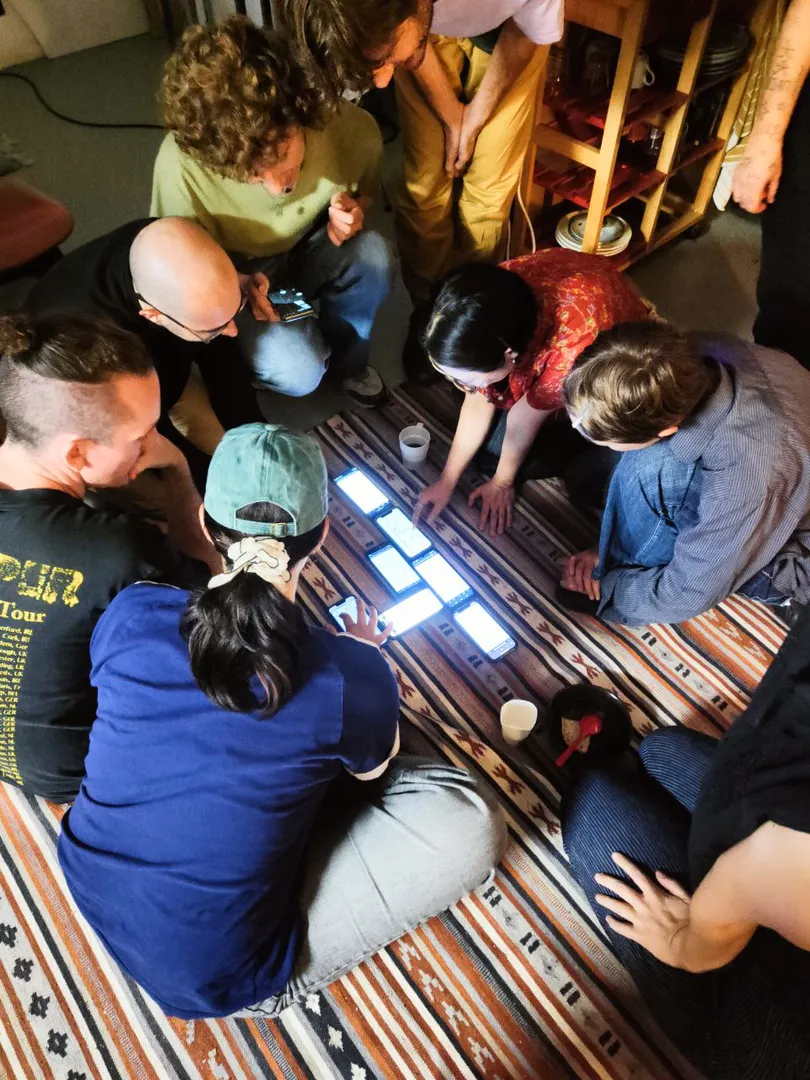 Seven people looking at seven phones on a carpet etc. etc.